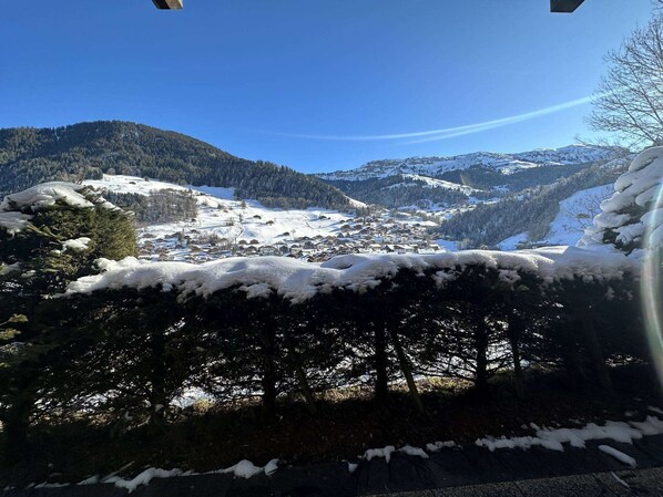 Paisaje montañoso nevado con un pueblo en el valle.