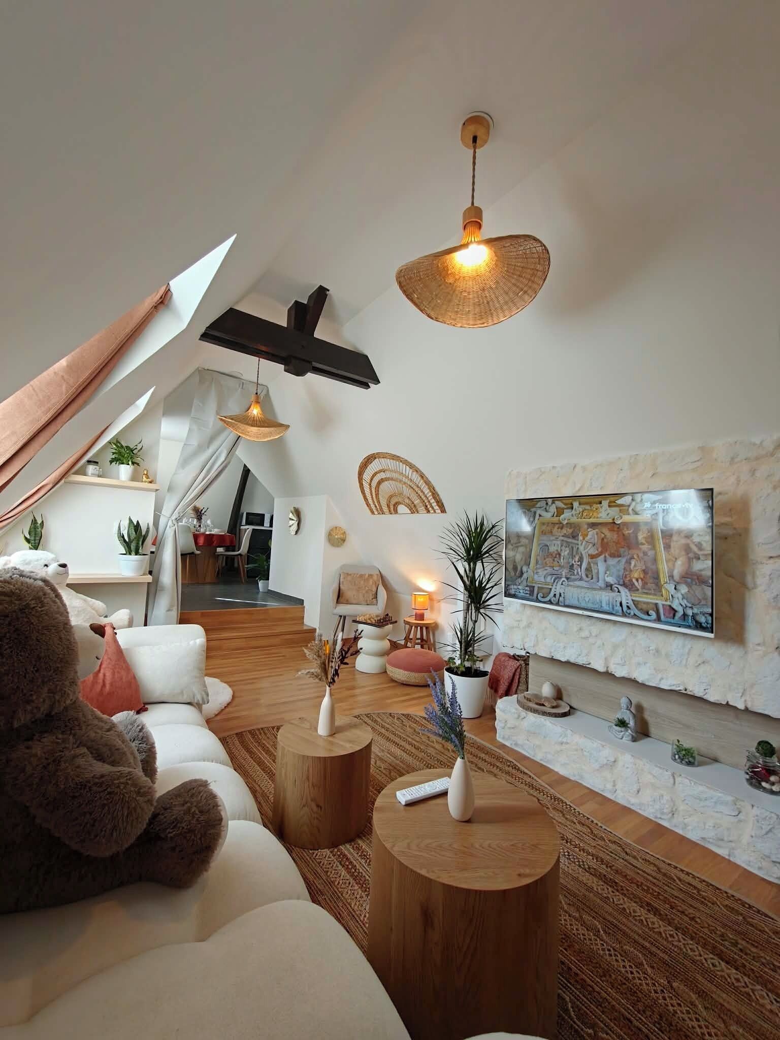 Una sala de estar moderna con techo inclinado, un cuadro grande y una zona de estar acogedora con un osito de peluche.