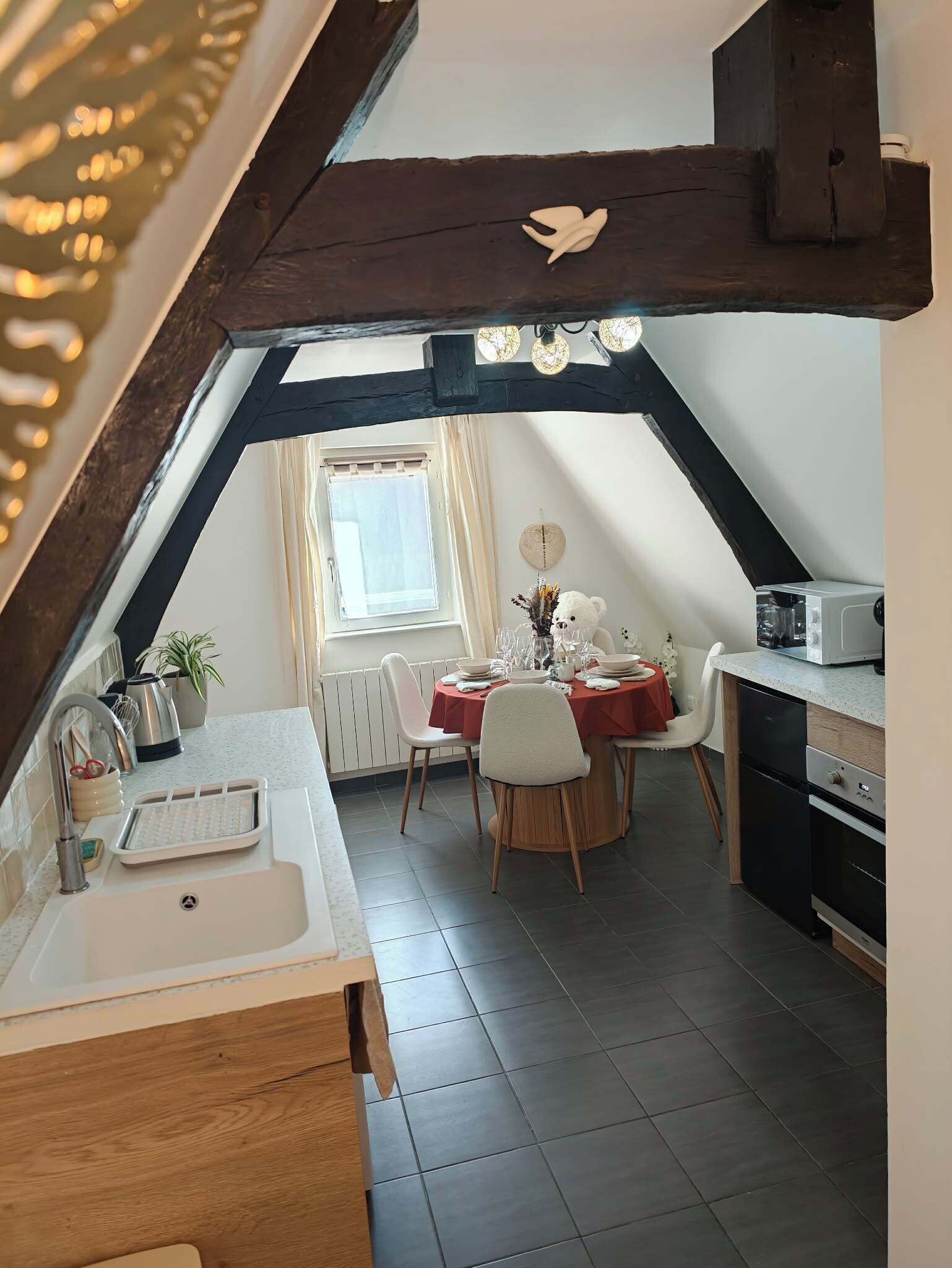 Een eethoek met een tafel gedekt voor twee personen, een decoratie van een witte beer en een raam met gordijnen.
