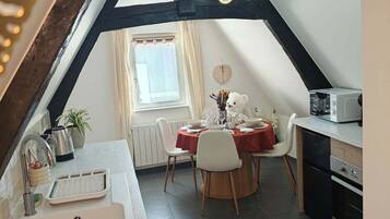 Een eethoek met een tafel gedekt voor twee personen, een decoratie van een witte beer en een raam met gordijnen.