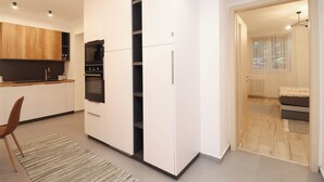 Una cocina moderna con armarios blancos, horno integrado y comedor con una silla y alfombra.