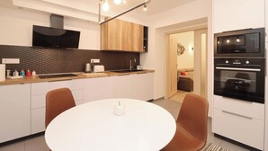 Una cocina moderna con una mesa de comedor blanca, sillas marrones y electrodomésticos integrados.