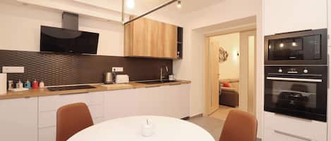 A modern kitchen with a white dining table, brown chairs, and built-in appliances.