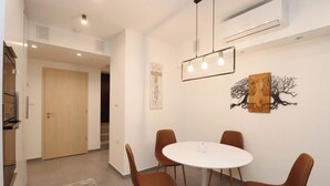Un moderno comedor con una mesa redonda y cuatro sillas, una lámpara colgante y decoración en la pared.