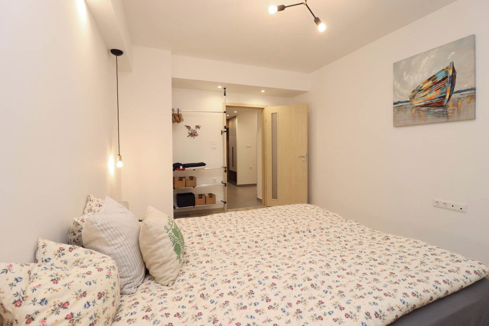 Um quarto com uma cama, um guarda-roupa, um espelho e um quadro na parede.
