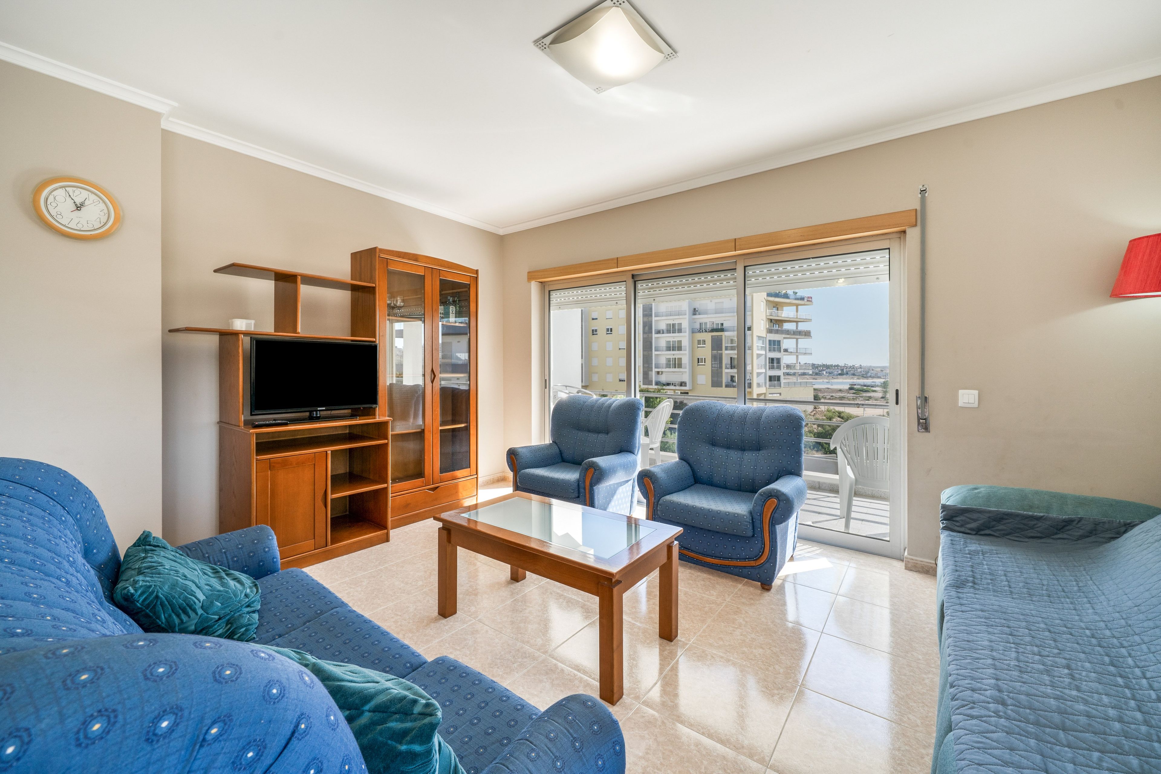 A living room with a television, two armchairs, a sofa, and a glass coffee table.