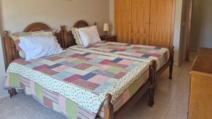 A bedroom with a wooden bed, a quilt, a nightstand, a wardrobe, and a framed picture on the wall. - Apartment 'Rocha Waves' with Balcony, Wi-Fi and Air Conditioning (Portimão)