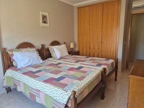 Ein Schlafzimmer mit einem hölzernen Bett, einer gesteppten Decke, einem Nachttisch, einem Kleiderschrank und einem gerahmten Bild an der Wand.