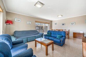 Ein Wohnzimmer mit einer Couch, Sesseln, einem Couchtisch und einem Essbereich mit Stühlen und einem Tisch.