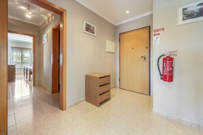 Ein Flur mit einem Holzkasten, einer Tür und einem Feuerlöscher an der Wand.