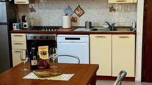 A kitchen with a dining table, chairs, a stove, a dishwasher, and a refrigerator. - Detached house just a few minutes from the beach (Castiglione della Pescaia)