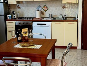 Eine Küche mit Esstisch, Stühlen, Herd, Geschirrspüler und Kühlschrank.