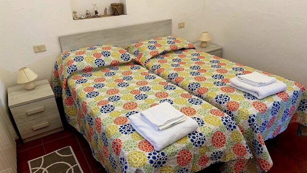 A double bed with floral-patterned bedding, two bedside tables with lamps, and a small rug on the floor. - Detached house just a few minutes from the beach (Castiglione della Pescaia)