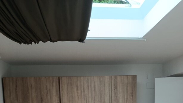 A bedroom with a large wardrobe, a chair, and a skylight. - Atalaya 4001 Ground-Floor Apartment (Arnuero)