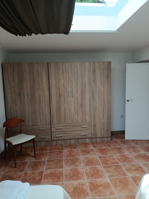 A bedroom with a large wardrobe, a chair, and a skylight. - Atalaya 4001 Ground-Floor Apartment (Arnuero)