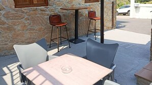 An outdoor seating area with stone walls, wooden shutters, and a view of the sea. - Atalaya 4001 Ground-Floor Apartment (Arnuero)