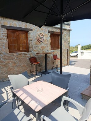 An outdoor seating area with stone walls, wooden shutters, and a view of the sea. - Atalaya 4001 Ground-Floor Apartment (Arnuero)