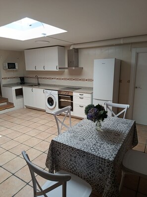A compact kitchen with a washing machine, a microwave, and a dining area with a table and chairs. - Atalaya 4001 Ground-Floor Apartment (Arnuero)