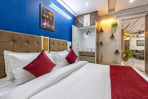 Habitación de hotel con cama, armario, espejo y puerta que da a otra habitación.