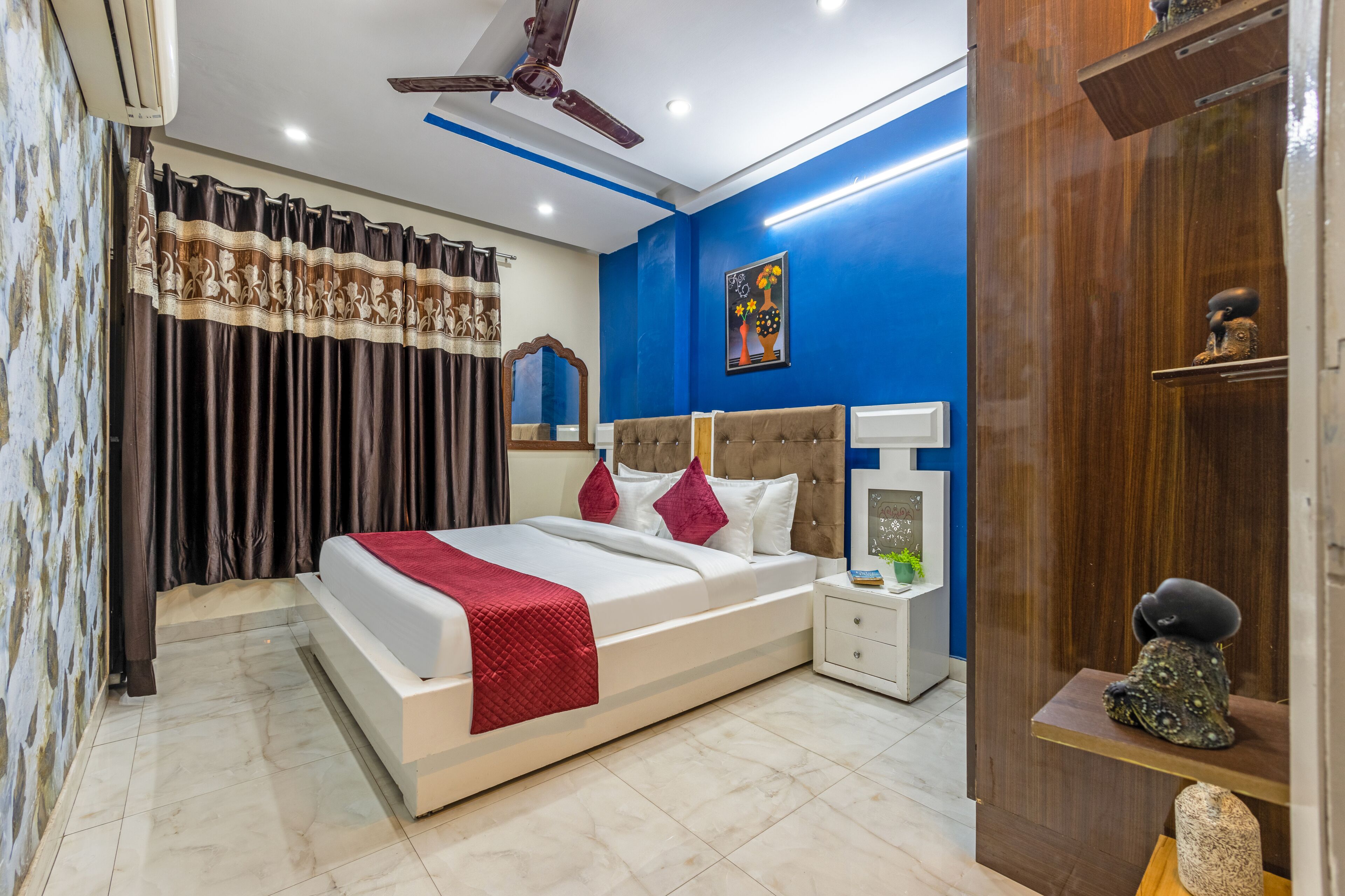 A modern bedroom with a bed, bedside tables, a nightstand, a ceiling fan, and a blue accent wall.