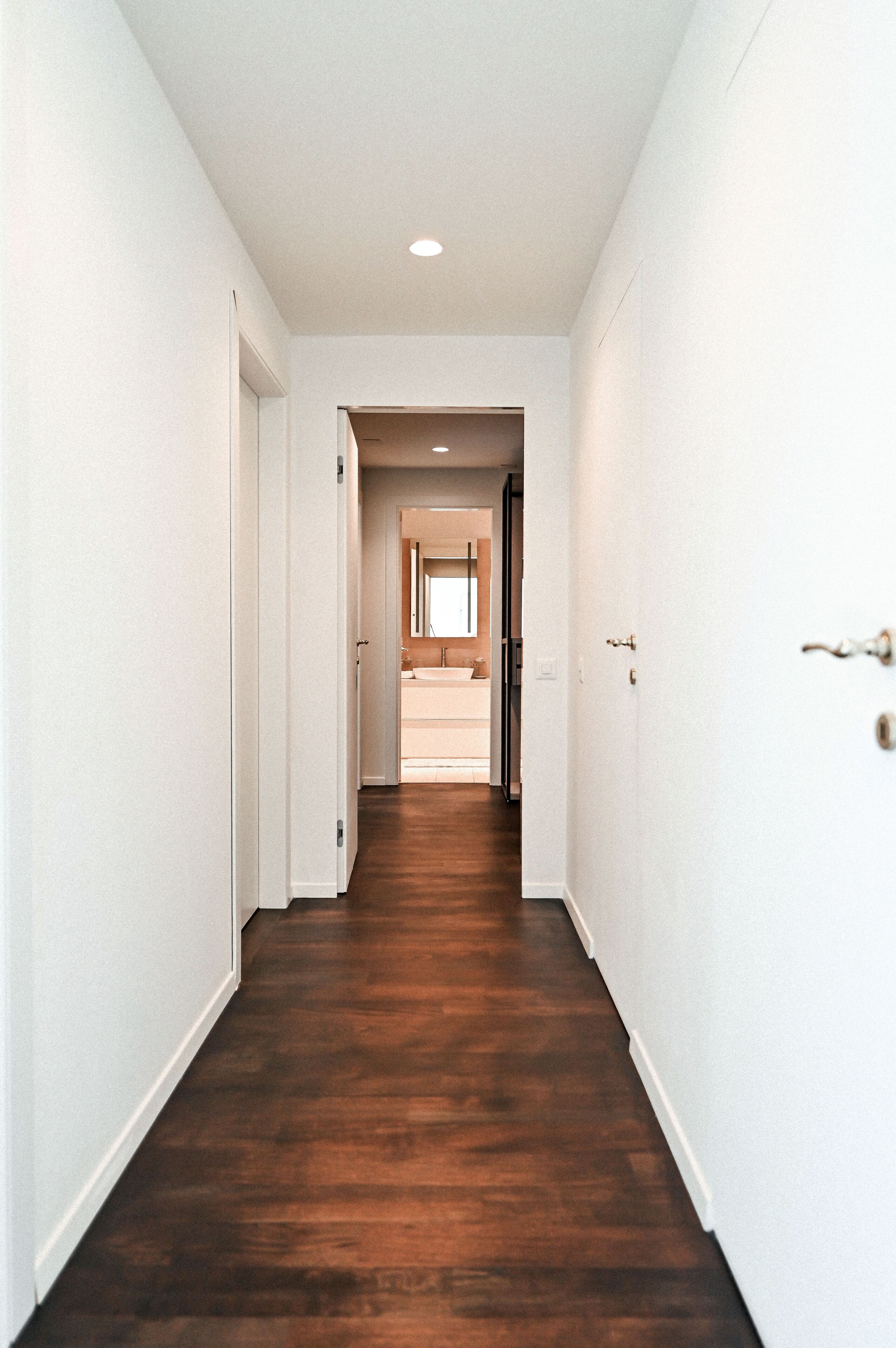 A hallway with a wooden floor and white walls.