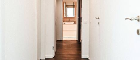 A hallway with a wooden floor and white walls.