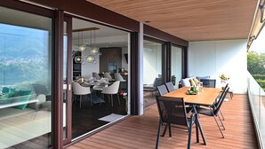 Uma sala de jantar moderna com mesa e cadeiras de madeira, uma divisória de vidro e vista para o interior.