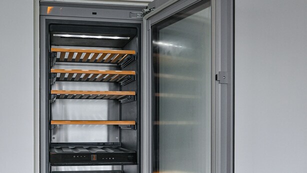 Uma geladeira moderna de aço inoxidável com várias prateleiras e porta de vidro, demonstrando um recurso para armazenamento e exibição de alimentos.