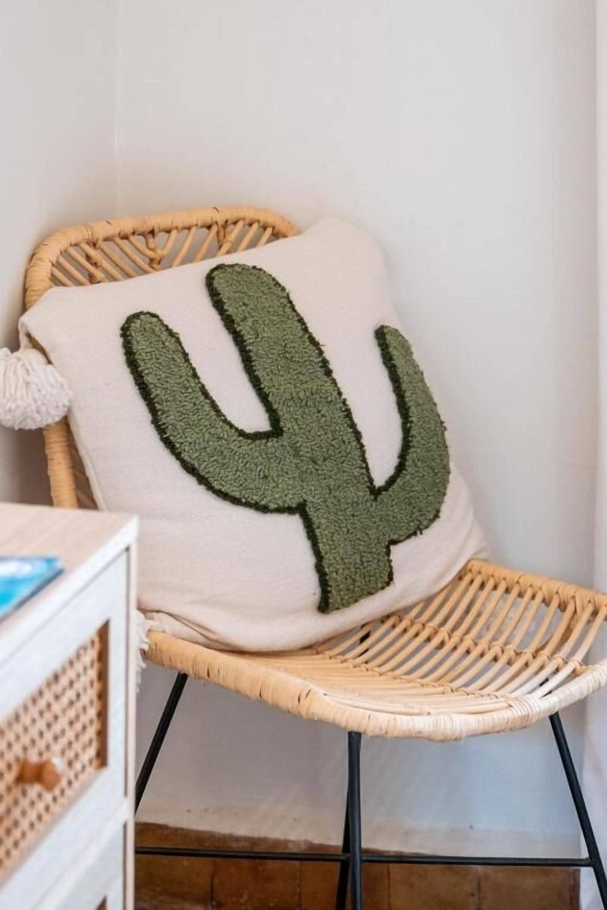 Uma cadeira de vime com almofada estampada com cactos.
