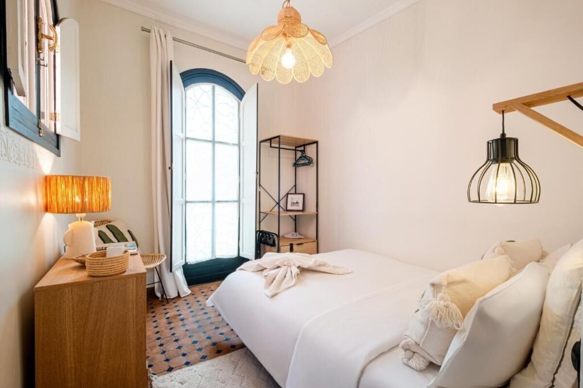 Ein Schlafzimmer mit einem Bett, Nachttisch, Lampe und einer Pendelleuchte.