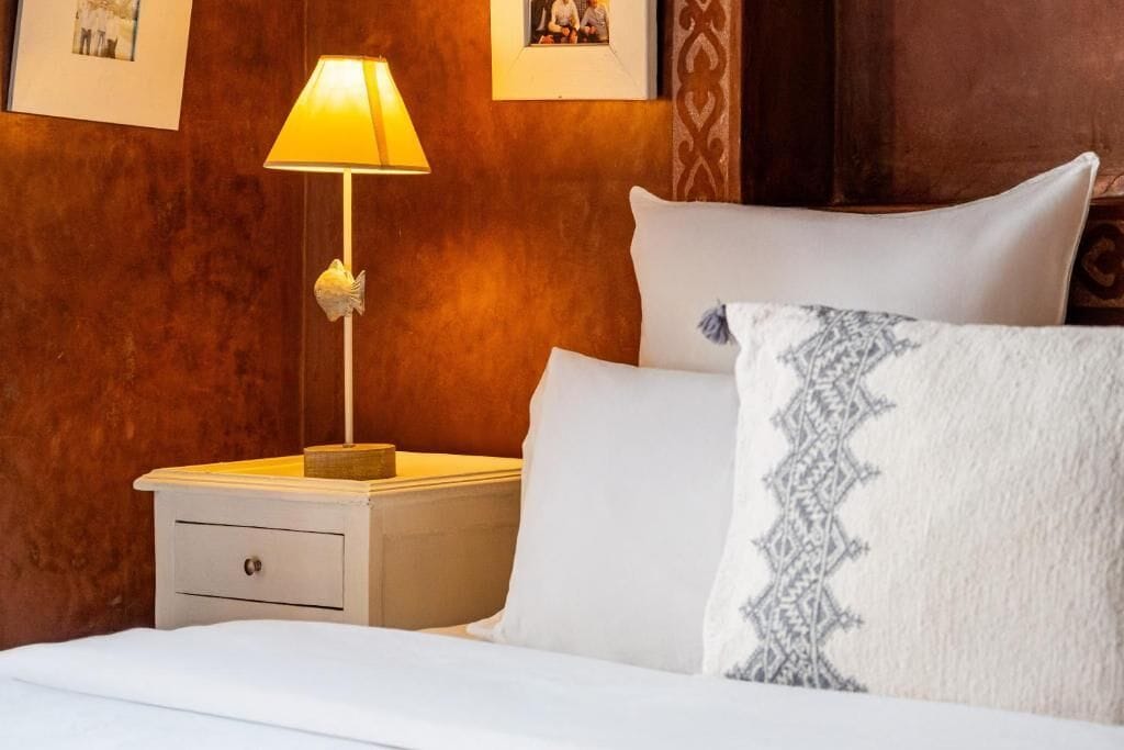 Une chambre d’hôtel avec un lit, une table de chevet avec une lampe et un mur orné de tableaux.