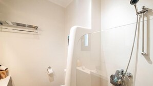 A modern bathroom with a glass shower enclosure, a toilet, a towel rack, and a basket of toiletries. - Riad Khiata (Marrakech)