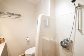 Ein modernes Badezimmer mit einer Glasdusche, einer Toilette, einem Handtuchhalter und einem Tablett mit Toilettenartikeln.
