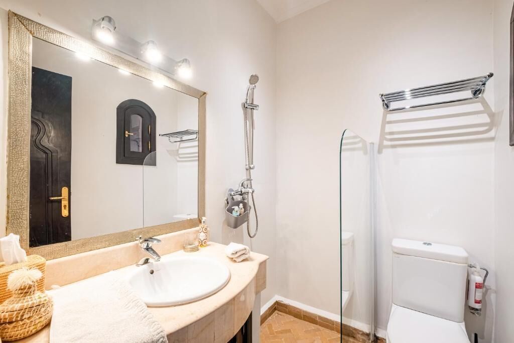 Un baño con lavamanos, espejo, ducha e inodoro.