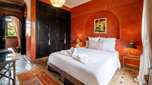 A hotel room with a large bed, a desk, a chair, and a small table with a lamp. - Riad Khiata (Marrakech)