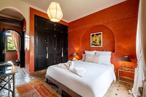 Ein Hotelzimmer mit einem großen Bett, einem Schreibtisch, einem Sessel und einem kleinen Tisch mit einer Lampe.