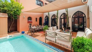 A pool area with a lounge chair, a table, and a dining setup. - Riad Khiata (Marrakech)