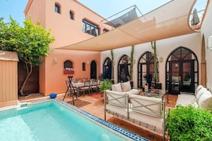 Ein Poolbereich mit Liegestuhl, Tisch und Essplatz.
