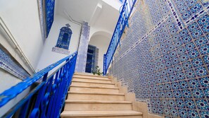 Un escalier avec des rampes bleues menant à une pièce dont le mur est orné d’un motif.