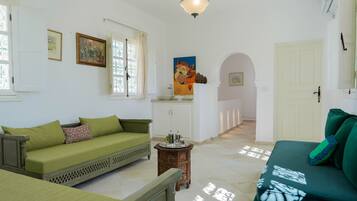 Una habitación con un sofá verde, una mesita de madera, un armario blanco y un cuadro en la pared.