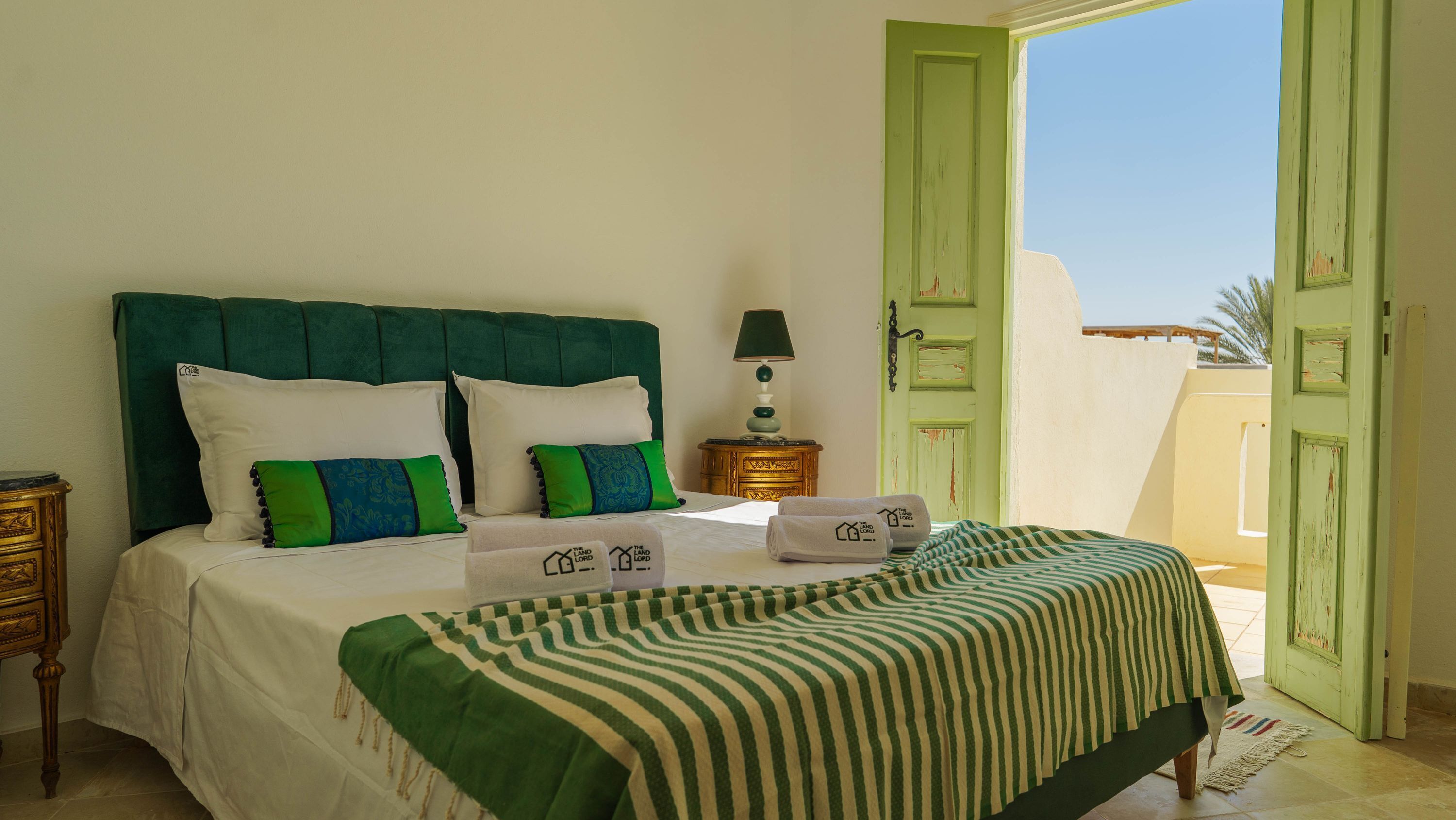 A hotel room with a bed, pillows, a lamp, and a view of the outside.