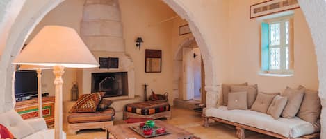 A cozy living room with a fireplace, a sofa, a coffee table, and a television.