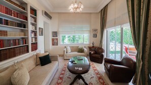 A well-lit living room with a sofa, armchairs, a coffee table, and a bookshelf filled with books. - Villa d Exception Gammarth Piscine Priv e (La Marsa)