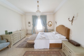 A bedroom with a bed, a dresser, a nightstand, a mirror, and a chandelier. - Villa d Exception Gammarth Piscine Priv e (La Marsa)