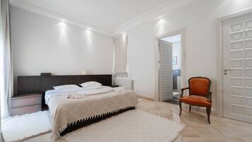 A bedroom with a bed, nightstands, a chair, and a door.