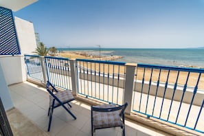 A balcony with two chairs and a view of the beach.