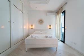 A hotel room with a large bed, two bedside lamps, a sunburst wall decoration, and a sliding glass door.
