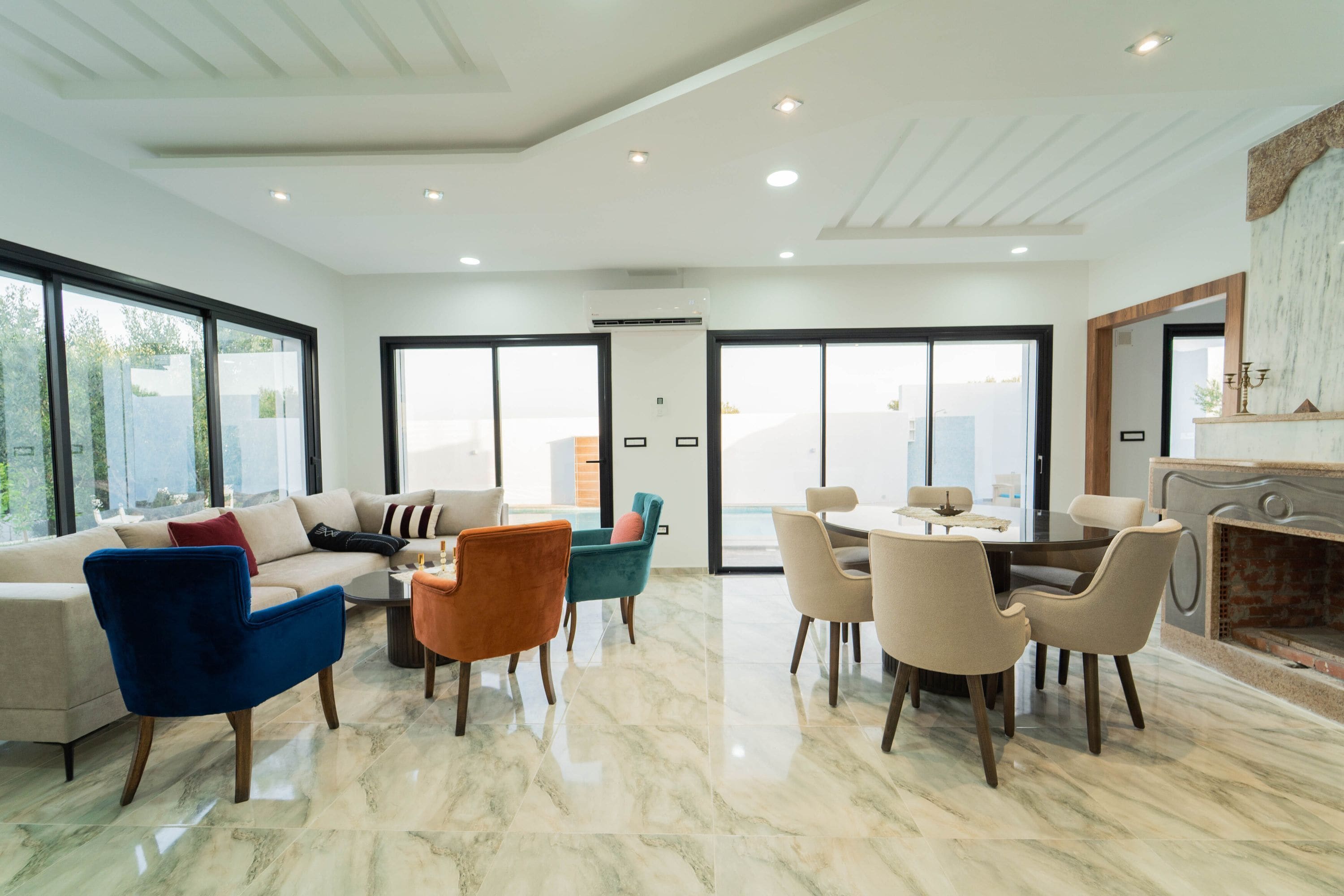 Un amplio salón con sofá, sillas, mesa de comedor y chimenea.