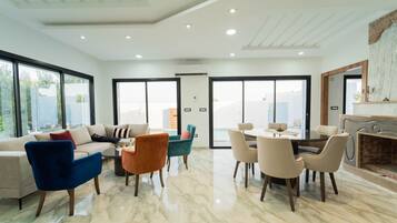 Un amplio salón con sofá, sillas, mesa de comedor y chimenea.
