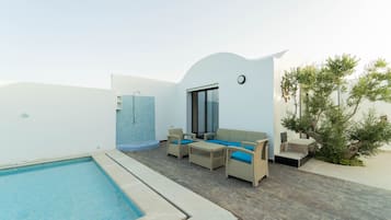 Un área de piscina con una zona de estar y un espacio pequeño con un muro de azulejos.